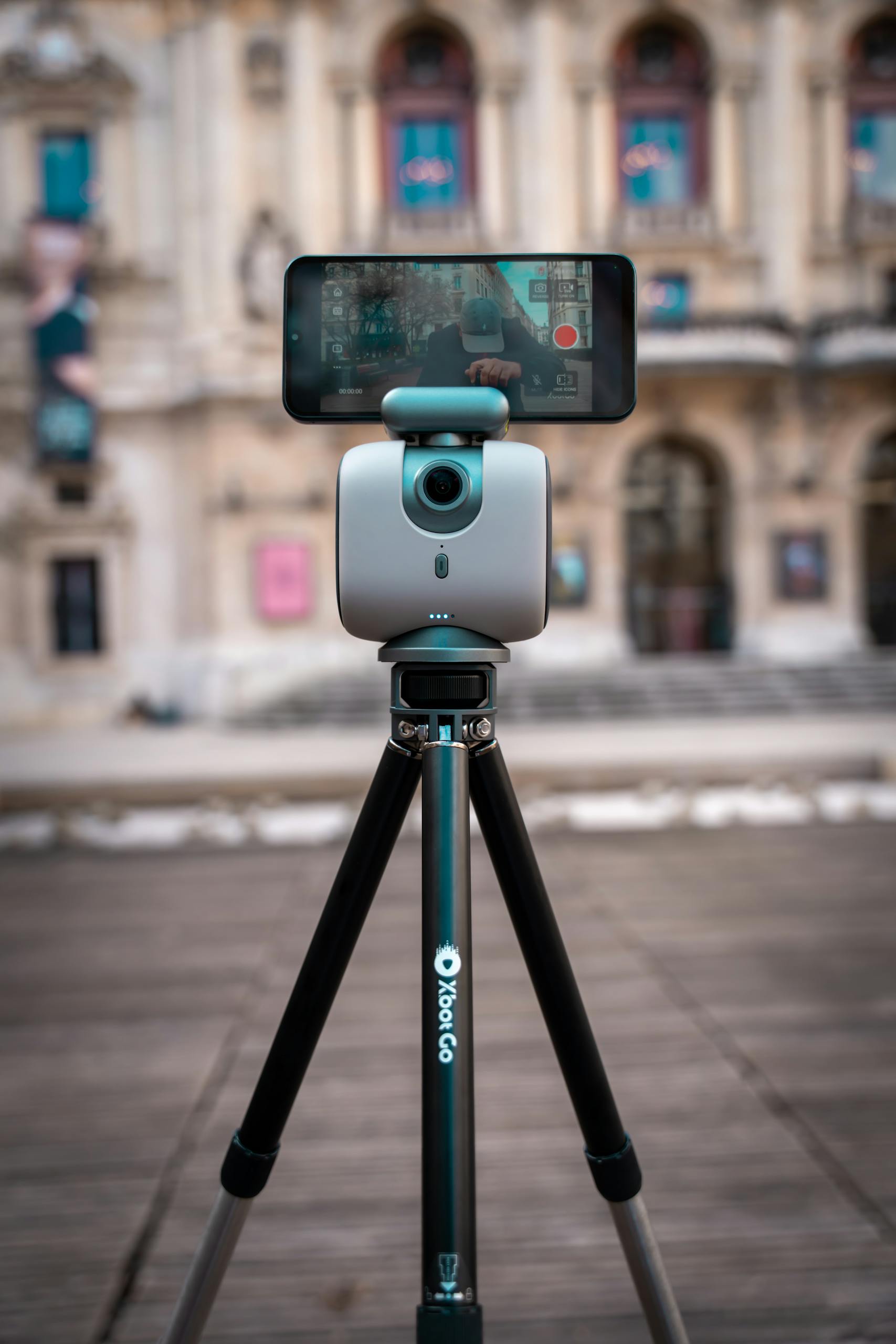 A smartphone mounted on a tripod capturing an architectural scene in daylight.
